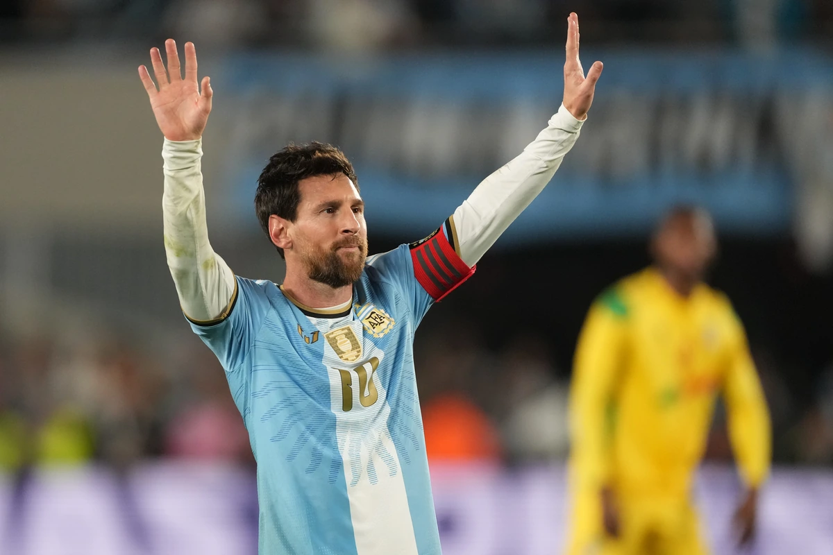 Lionel Messi in an Argentina shirt with both arms raised.